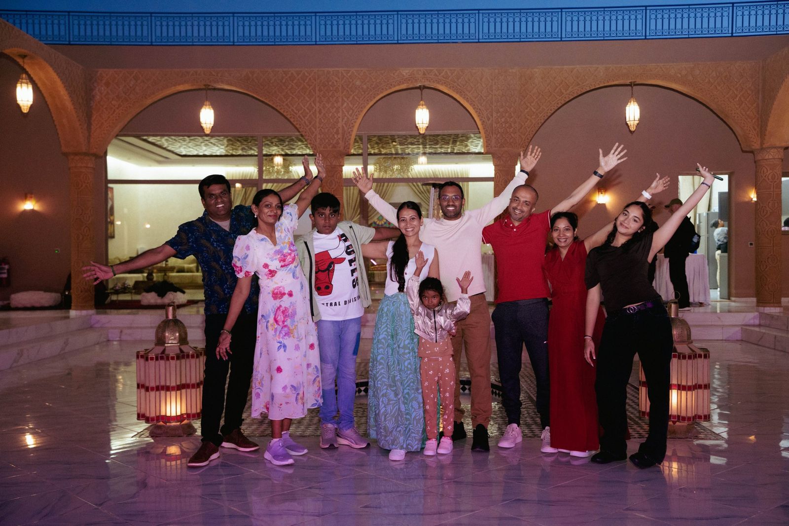 Group of happy travellers with raised arms in a Moroccan-style courtyard