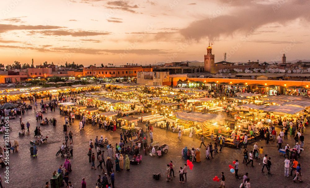 Het Jemaa el-Fna-plein bij zonsondergang terwijl de kraampjes verlicht worden